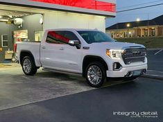 a white truck is parked in front of a building with red lights on the side