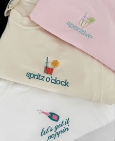 three shirts with embroidered logos on them sitting next to each other