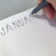 someone is writing the word january on a piece of paper with a pen in their hand