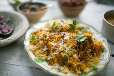 a plate full of food sitting on a table next to bowls of vegetables and sauces