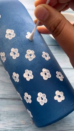 a hand holding a toothbrush in front of a blue case with white flowers on it