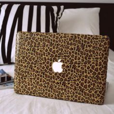 an apple laptop sitting on top of a bed next to pillows and pillow cases,