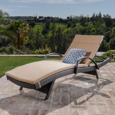 an outdoor chaise lounge chair sitting on a brick patio next to a lush green field