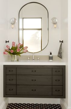 a bathroom with a sink, mirror and flowers in the vase on the counter top