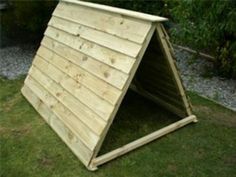 a wooden shelter sitting on top of a lush green field