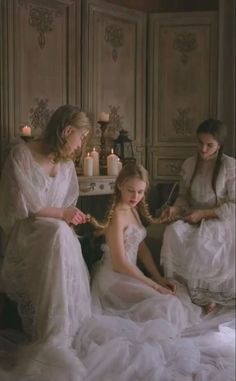 three women in white dresses are sitting on the floor