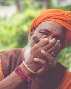 an old man with orange turban holding his hands together