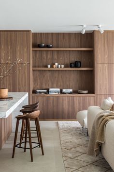 a living room filled with furniture next to a counter top and bookshelf on the wall