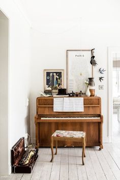 an old piano in the corner of a living room with white walls and wood floors