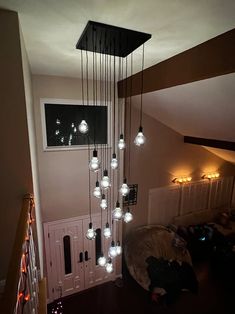 a chandelier hanging from the ceiling in a living room with lights on it