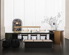 a black table with two benches and some vases on it in front of a white wall