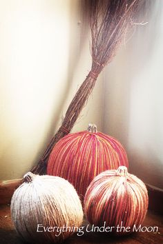 two pumpkins sitting on the floor next to a broom and some dry grass in front of a window