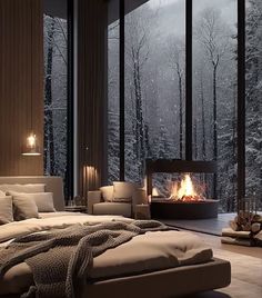 a bedroom with a fireplace in the middle and lots of windows to look out on snow covered trees