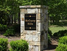 the sign for mccerry hills is in front of some bushes and trees with green leaves