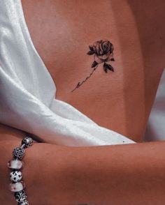 a woman's arm with a rose tattoo on her left side ribcage