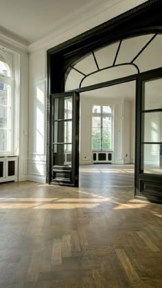 an empty room with wooden floors and black doors