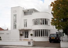 a car parked in front of a large white building with windows and balconies