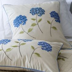 two pillows with blue flowers and green leaves on them