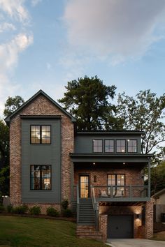 a brick and stone house with two story windows on the second floor is lit up at night