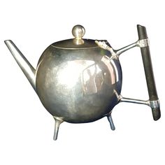 a metal teapot with two tongs sticking out of it's side, on a white background