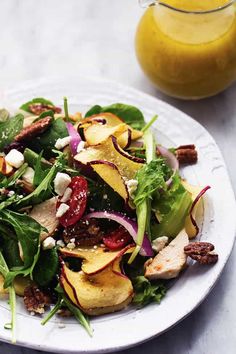 a white plate topped with salad next to a glass of orange juice