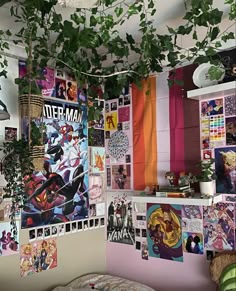 a room filled with posters and plants hanging from the ceiling next to a bed covered in blankets