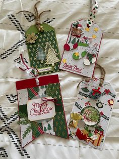 three tags with christmas designs on them sitting on a bed