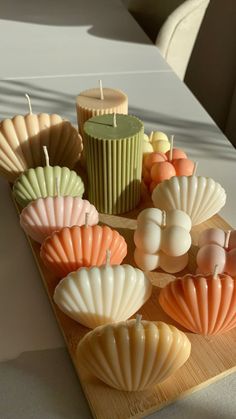 candles and seashells are arranged on a wooden tray next to a candle holder