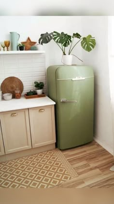 a green refrigerator sitting in the corner of a kitchen next to a potted plant