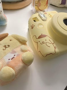 a stuffed animal next to a camera on top of a white table with other items