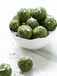 a bowl filled with green balls covered in powdered sugar