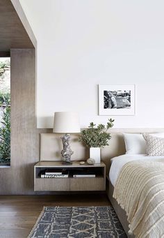 a bed room with a neatly made bed next to a window and a rug on the floor