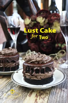 two chocolate cakes sitting on top of white plates next to wine glasses and vases