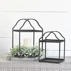 two black metal lanterns with succulents in them on top of a table