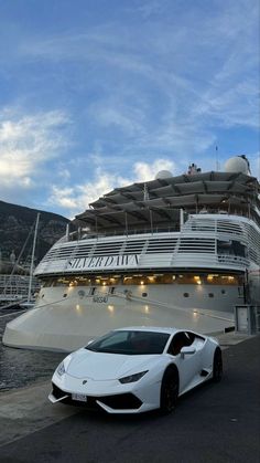 a white sports car parked in front of a large cruise ship with a sky background