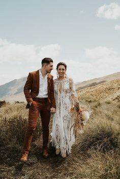 a bride and groom walking together in the mountains