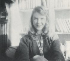 an old photo of a woman sitting in front of a bookshelf