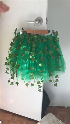 a green tutu skirt hanging on a clothes rack in front of a white wall