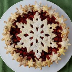 a white plate topped with a pie covered in icing and snowflakes