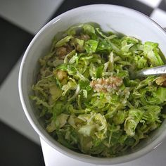 a white bowl filled with lettuce on top of a checkered tablecloth