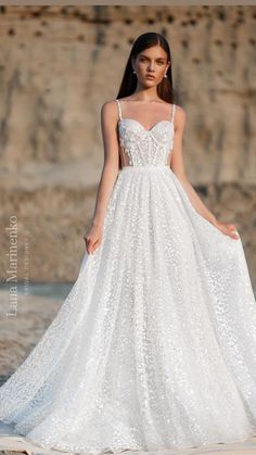 a woman in a wedding dress standing on the beach