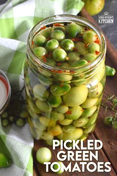 pickled green tomatoes in a glass jar on a wooden table with text overlay