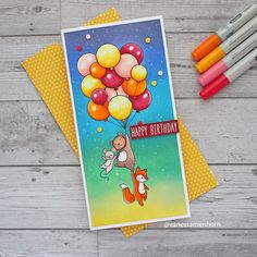 a happy birthday card with balloons and animals on it, next to crayons