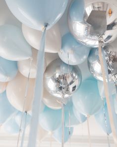 blue and white balloons are hanging from the ceiling