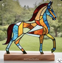 a stained glass horse standing on top of a wooden stand