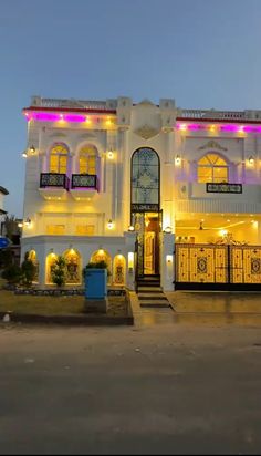 a large white building with many windows and lights on it's front entrance at night