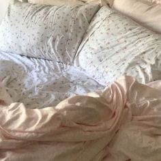 an unmade bed with pink sheets and pillows