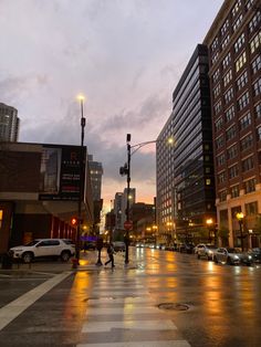 people are crossing the street at dusk on a rainy day