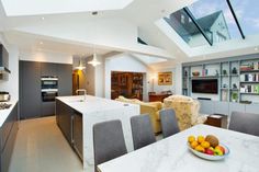 an open kitchen and dining room with skylights above the countertop, along with a bowl of fruit on the table