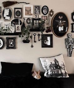 a living room filled with lots of framed pictures on the wall above a couch covered in black and white pillows